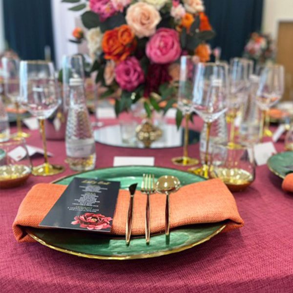 Green glass charger plate with gold rim on a set table